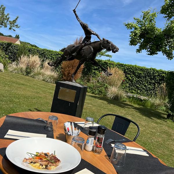 Table en terrasse face à une sculpture de joueur de polo